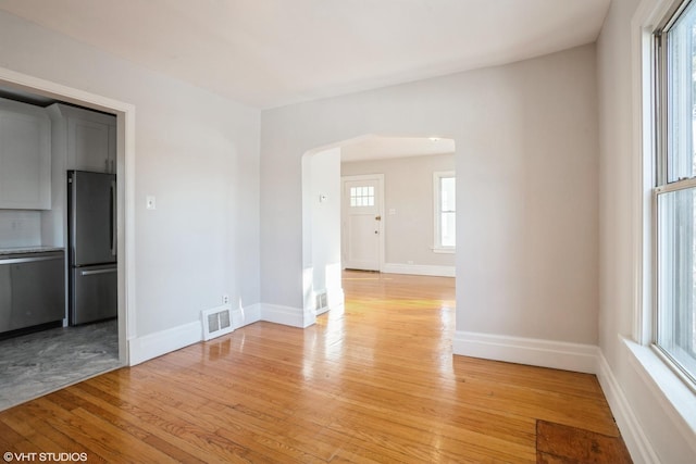 empty room with light wood-type flooring and plenty of natural light