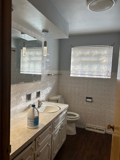 bathroom with tile walls, toilet, vanity, and hardwood / wood-style floors