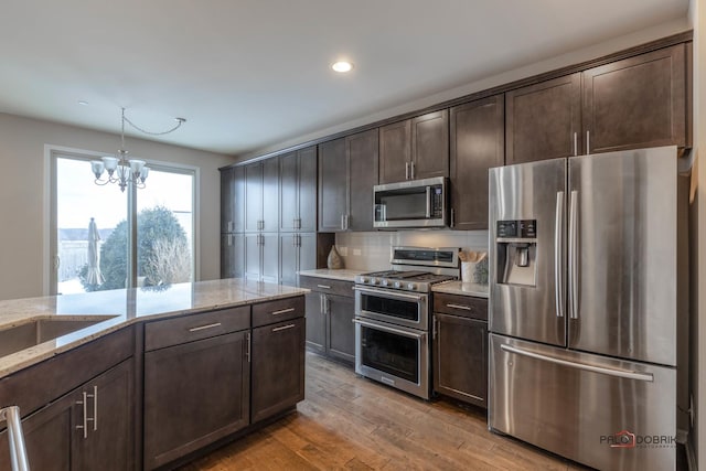 kitchen featuring decorative light fixtures, stainless steel appliances, a chandelier, and dark brown cabinetry