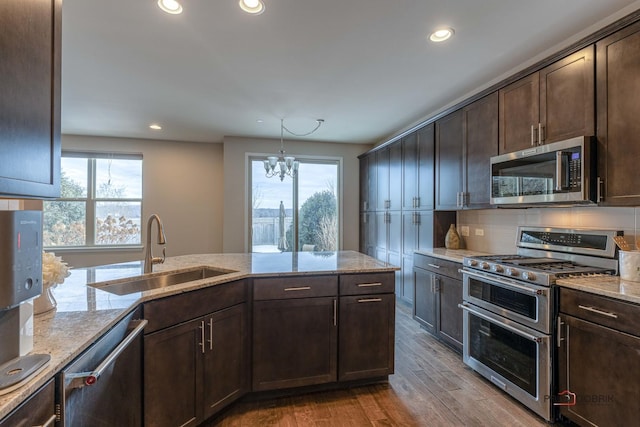 kitchen with a chandelier, stainless steel appliances, light stone countertops, sink, and light hardwood / wood-style flooring