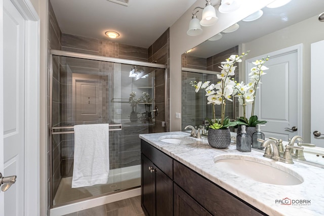 bathroom featuring a shower with door and vanity