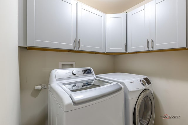 clothes washing area with washing machine and clothes dryer and cabinets