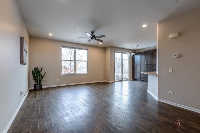 unfurnished living room with ceiling fan with notable chandelier and dark hardwood / wood-style floors