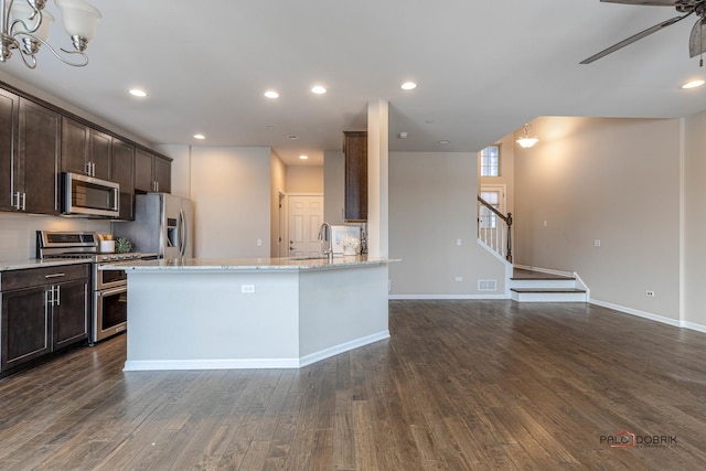 kitchen featuring light stone countertops, stainless steel appliances, dark hardwood / wood-style floors, and dark brown cabinetry