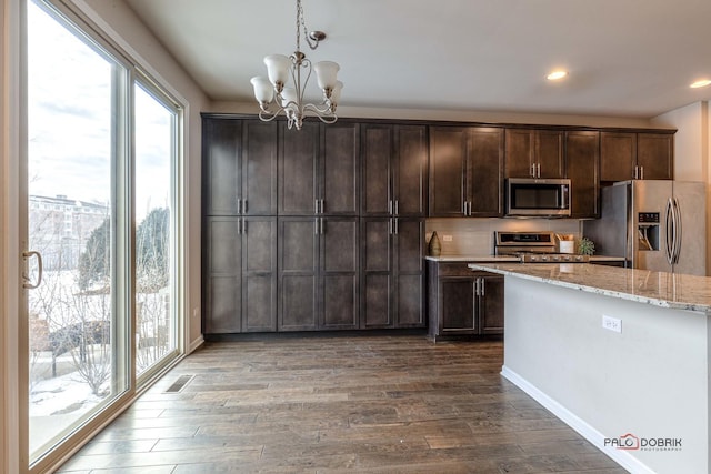 kitchen featuring an inviting chandelier, hardwood / wood-style floors, dark brown cabinetry, pendant lighting, and appliances with stainless steel finishes