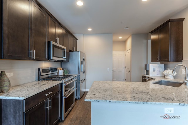 kitchen featuring light stone counters, dark hardwood / wood-style floors, stainless steel appliances, backsplash, and sink