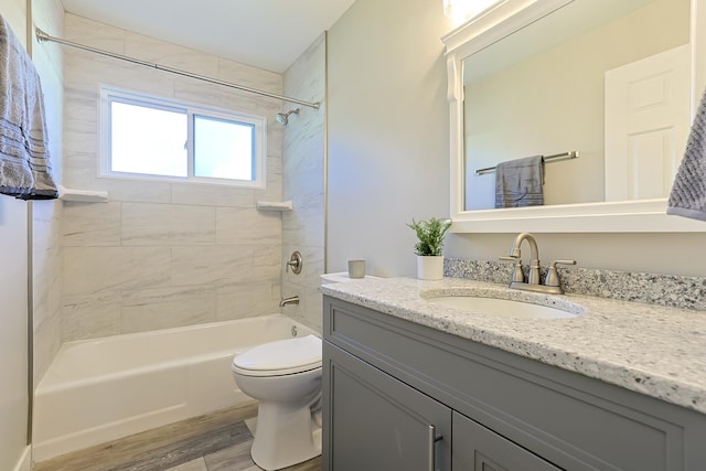 full bathroom with toilet, tiled shower / bath, wood-type flooring, and vanity