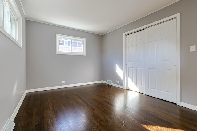 unfurnished bedroom with ornamental molding, a closet, and dark hardwood / wood-style floors