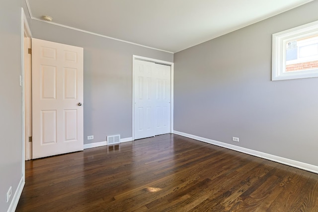 unfurnished bedroom with dark wood-type flooring and a closet