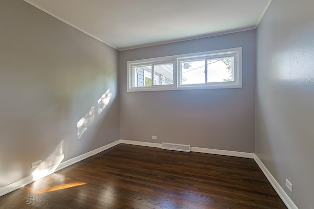 spare room featuring crown molding and dark wood-type flooring