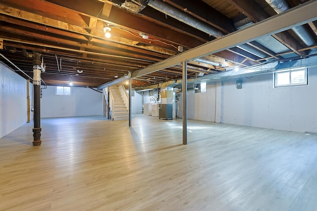 basement with hardwood / wood-style floors, heating unit, and washing machine and clothes dryer