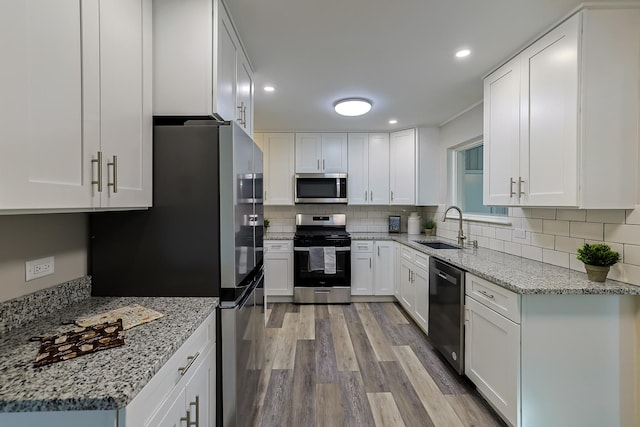 kitchen featuring sink, stainless steel appliances, white cabinetry, and light stone countertops