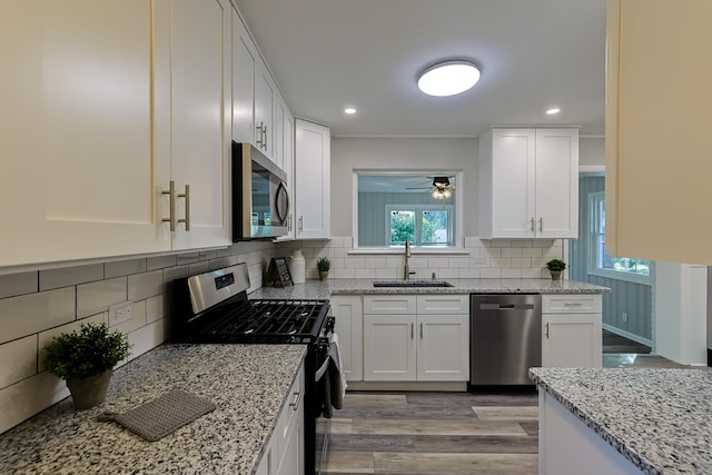 kitchen with sink, white cabinetry, light hardwood / wood-style flooring, and appliances with stainless steel finishes