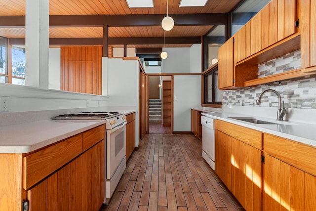 kitchen featuring pendant lighting, tasteful backsplash, sink, beam ceiling, and white appliances