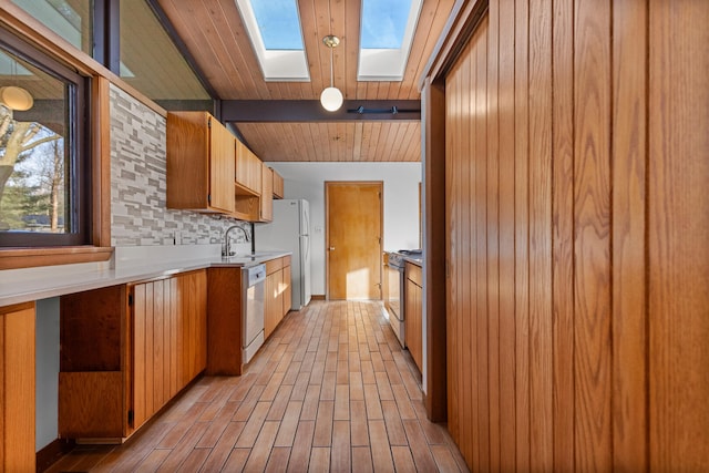 kitchen featuring appliances with stainless steel finishes, decorative backsplash, light wood-type flooring, and a skylight