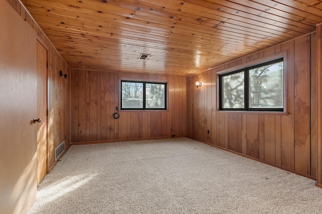 spare room with light colored carpet, wooden ceiling, and wood walls