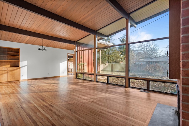 unfurnished sunroom featuring an inviting chandelier and lofted ceiling with beams