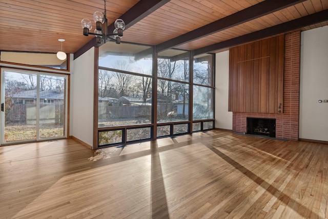 unfurnished living room with a wall of windows, a fireplace, beam ceiling, and light hardwood / wood-style flooring