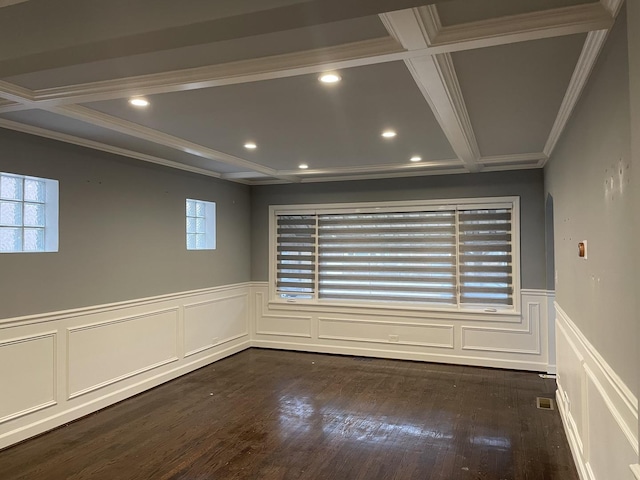 empty room with dark wood-type flooring, a wainscoted wall, coffered ceiling, and ornamental molding