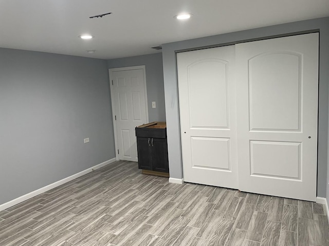 unfurnished bedroom featuring recessed lighting, a closet, light wood finished floors, and baseboards