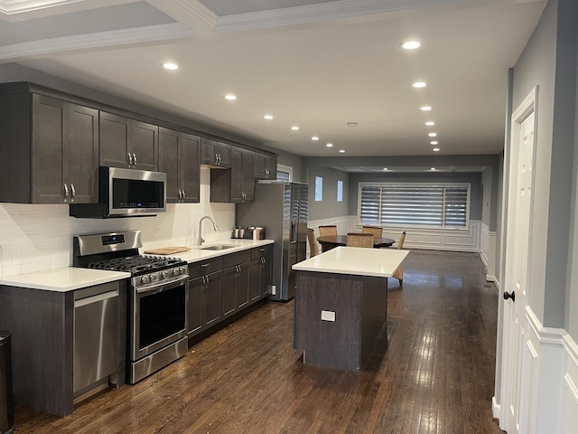 kitchen with a center island, stainless steel appliances, light countertops, dark wood-type flooring, and a sink