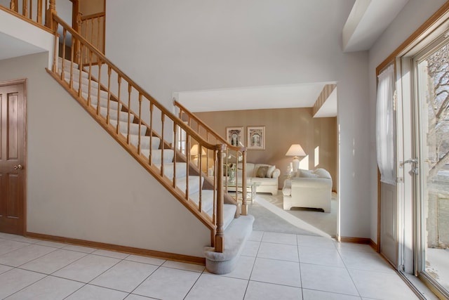 tiled entrance foyer featuring baseboards and stairs