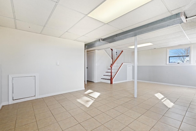 basement with a drop ceiling and light tile patterned floors