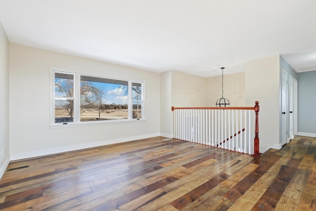 empty room with a chandelier and dark hardwood / wood-style floors