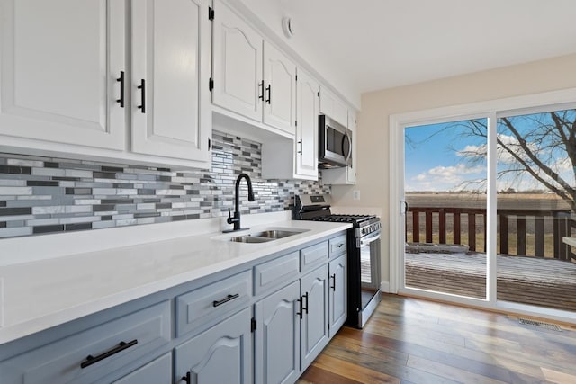 kitchen with sink, white cabinets, tasteful backsplash, dark wood-type flooring, and stainless steel appliances