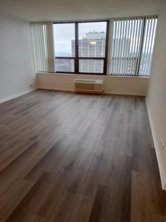 empty room with dark hardwood / wood-style floors and a wall mounted air conditioner