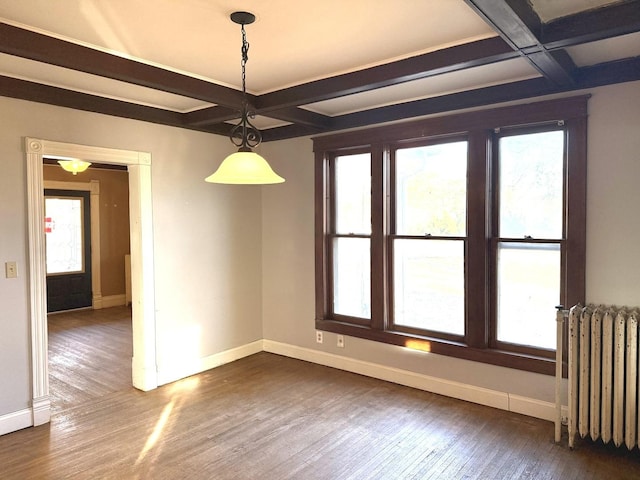 empty room featuring a healthy amount of sunlight, radiator, beam ceiling, and coffered ceiling