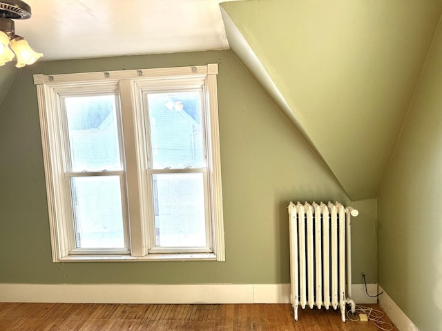 additional living space with radiator, vaulted ceiling, and hardwood / wood-style flooring