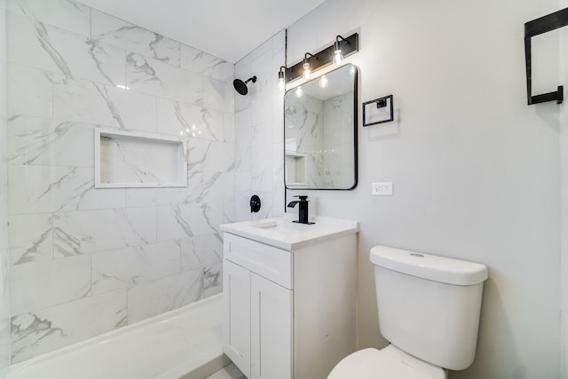 bathroom with toilet, a tile shower, and vanity