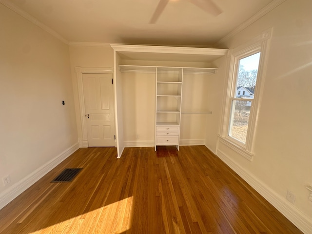 unfurnished bedroom with a closet, ceiling fan, crown molding, and dark hardwood / wood-style floors