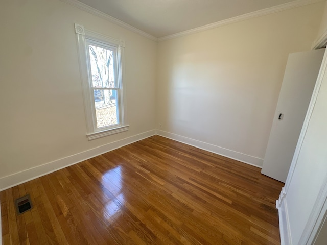 spare room with dark wood-type flooring and crown molding