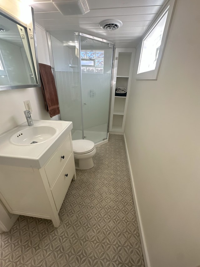 bathroom featuring vanity, a shower with shower door, and toilet