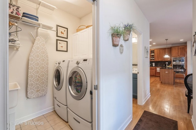 laundry room with cabinets, light tile patterned floors, and washing machine and clothes dryer