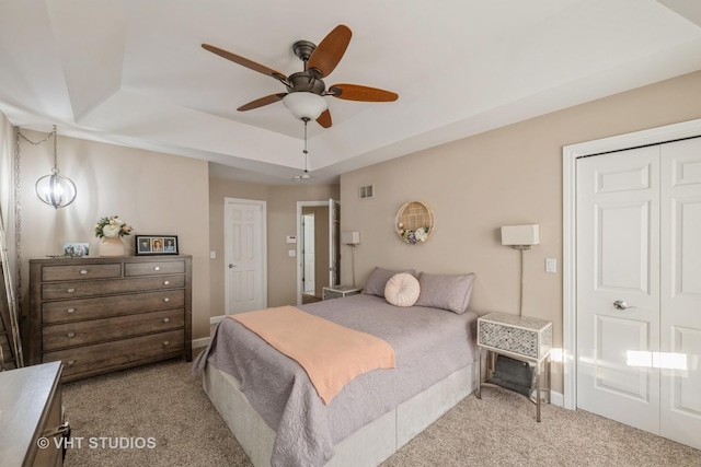 carpeted bedroom with a tray ceiling and ceiling fan