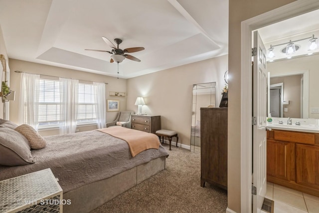 carpeted bedroom featuring ceiling fan, a tray ceiling, and sink