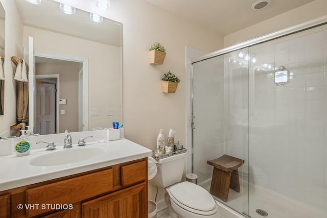 bathroom featuring vanity, a shower with door, and toilet