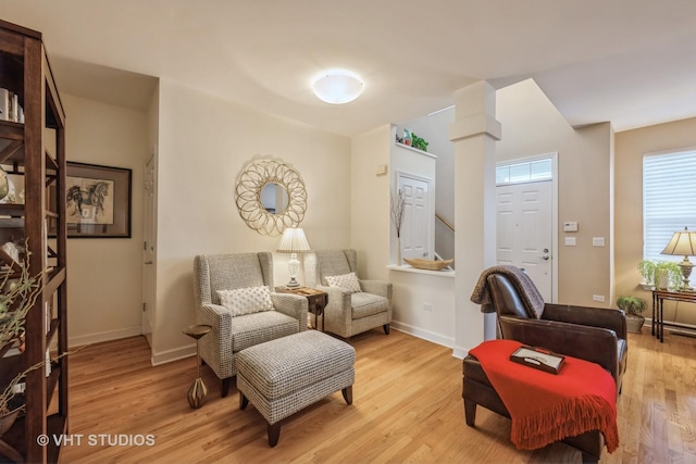 living area with light hardwood / wood-style floors and decorative columns