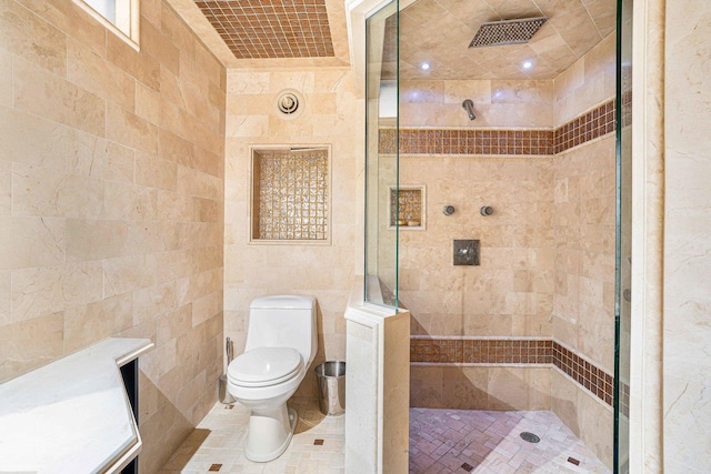 bathroom featuring toilet, tile walls, tiled shower, and tile patterned flooring