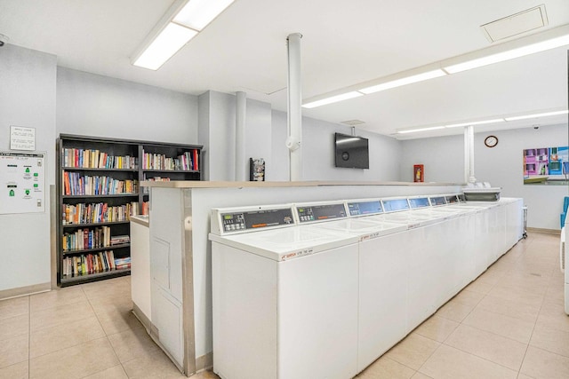 kitchen featuring separate washer and dryer, light tile patterned flooring, and white cabinets