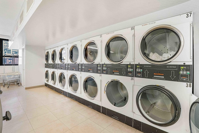 laundry area featuring washing machine and dryer, light tile patterned floors, and stacked washer and clothes dryer