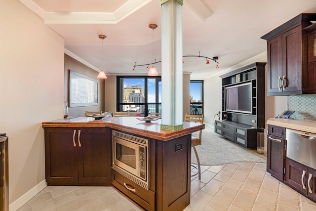 kitchen featuring pendant lighting, a kitchen bar, crown molding, stainless steel microwave, and dark brown cabinets