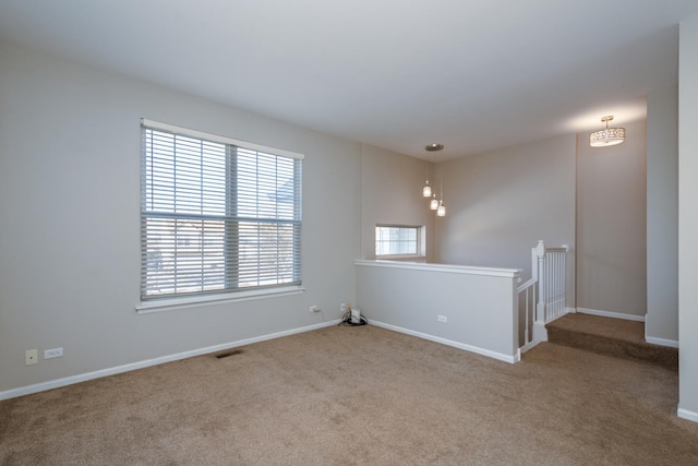 carpeted spare room featuring a notable chandelier