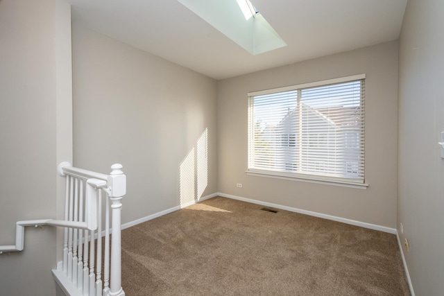 carpeted spare room featuring a skylight