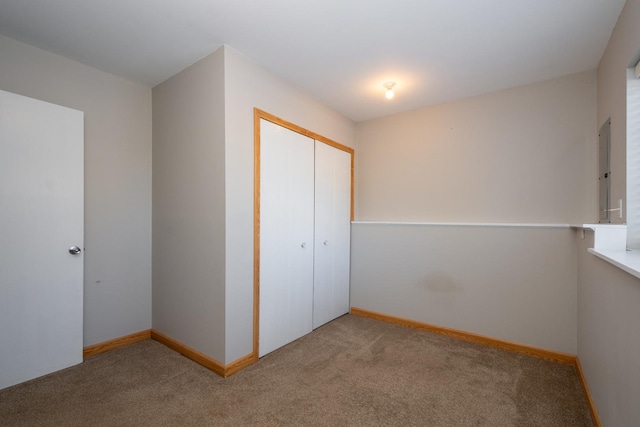 unfurnished bedroom featuring electric panel, a closet, and light carpet