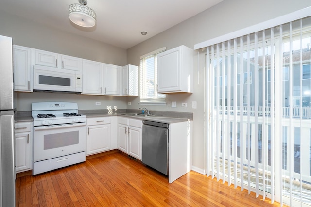 kitchen with white appliances, white cabinets, light hardwood / wood-style floors, and sink