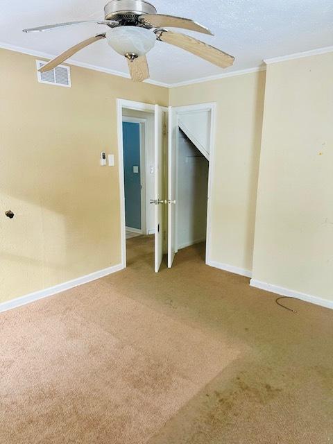 empty room with ceiling fan, carpet flooring, and ornamental molding